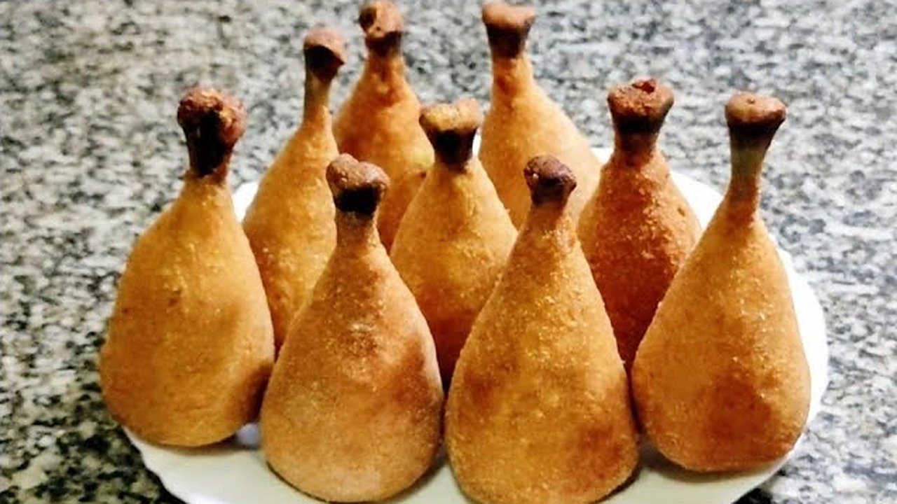 Coxas creme empanadas e douradas, modeladas no formato de coxa de frango com o ossinho, servidas em prato branco