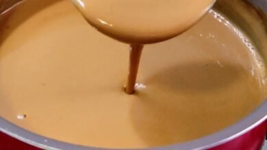 Leite queimado cremoso sendo mexido em panela vermelha