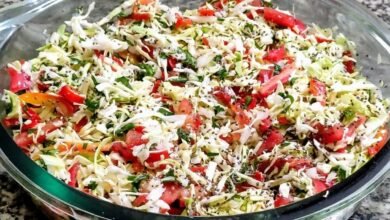Salada de repolho crocante com tomate em tirinhas, cheiro-verde e gergelim em uma travessa de vidro